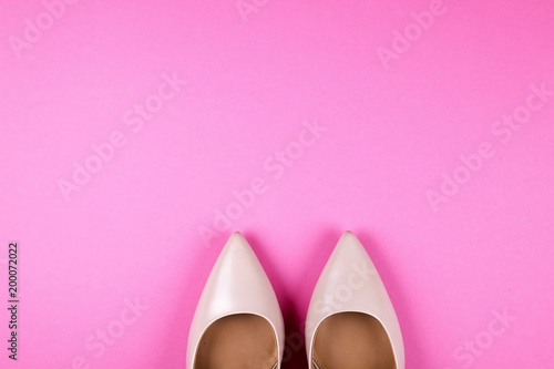 Stylish classic women's beige leather shoes with medium high heels shot from top on pale pink background. Copy space, top view, flat lay. Shoe sale / clearance ad concept.