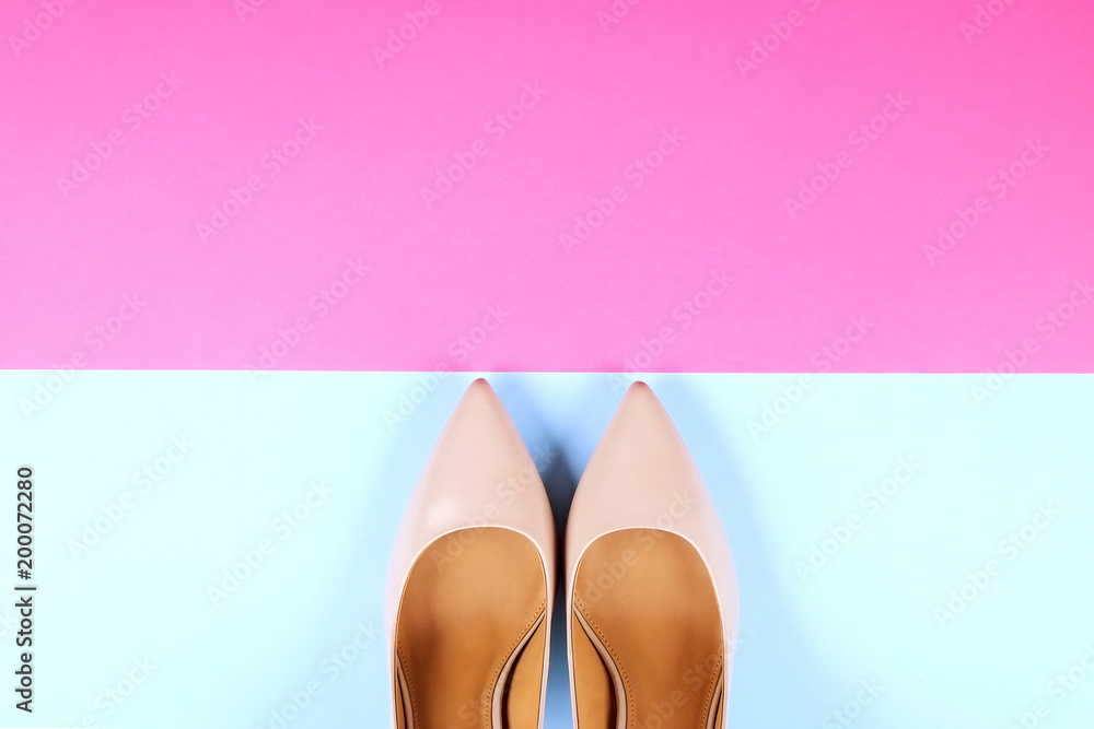Stylish classic women's beige leather shoes with medium high heels shot from top on pink blue multi-colored paper background. Copy space, top view, flat lay. Shoe sale / clearance ad concept. Stylish classic women's beige leather shoes with medium high heels shot from top on pink blue multi-colored paper background. Copy space, top view, flat lay. Shoe sale / clearance ad concept.