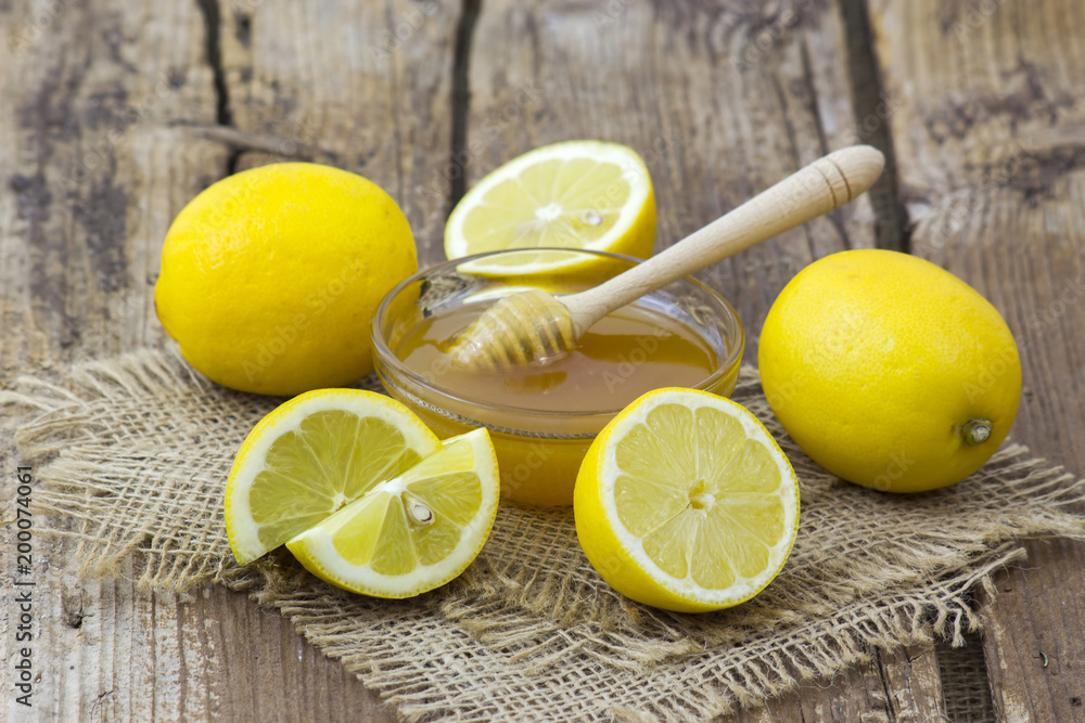 bowl with honey and fresh lemons on wooden background