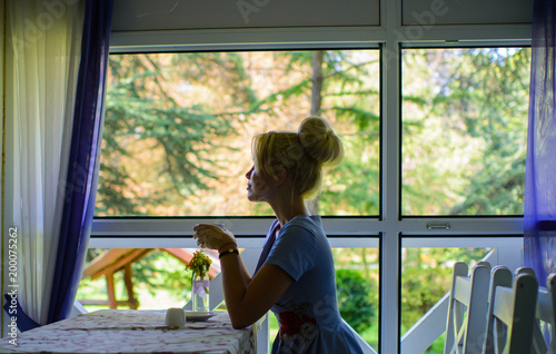 Silhouette of woman in front of window, nature background.