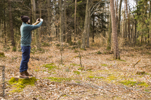 man taking photo with smartphone in the forest