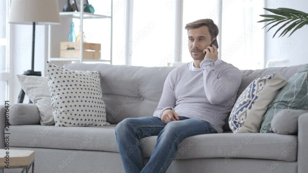 Adult Man Talking on Phone while Sitting on Couch Adult Man Talking on Phone while Sitting on Couch