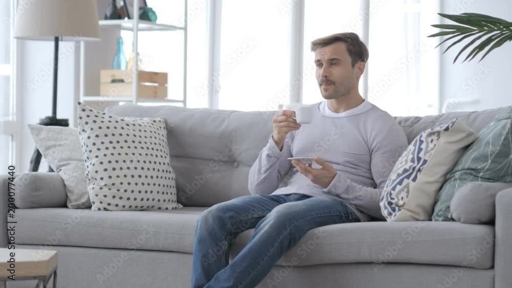 Adult Man Drinking Coffee and Relaxing on Couch Adult Man Drinking Coffee and Relaxing on Couch