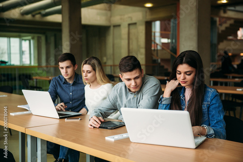 Group of college students studying in the school library, a girl and a boy are using a laptop and connecting to internet