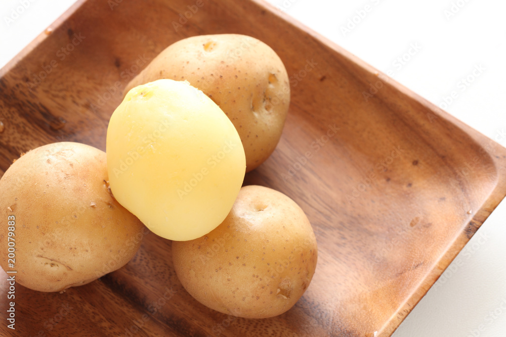 Multiple boiled new potato on wooden plate Multiple boiled new potato on wooden plate