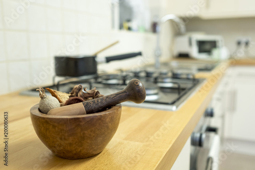 A hand turned wooden Pestle and Mortar filled with pot pourri place on a beech wood kitchen worktop. photo