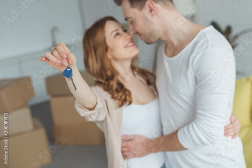 happy young couple holding key from new apartment and smiling each other