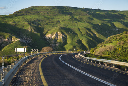 Serpentine countryside highway road in the mountains at sunset time. Location: Golan Heights, against Tiberias (Tveria), Israel