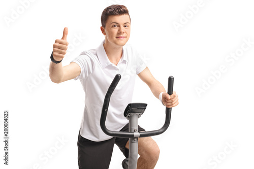 Teenage boy on an exercise bike making a thumb up sign