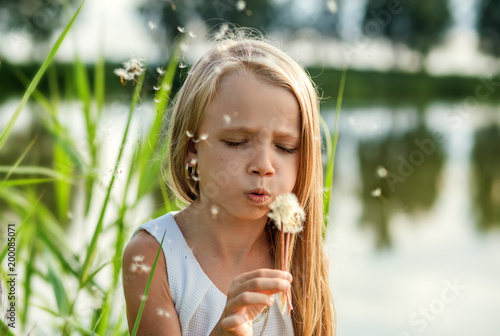  girl blowing on dandelion, summer in nature
