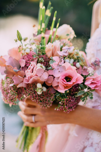 wedding bouquet in the hands of the bride against nature background, close-up