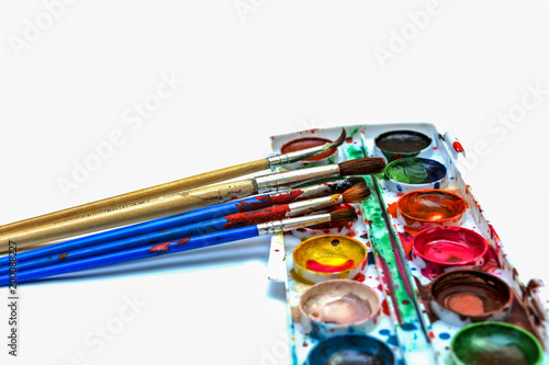 Old brushes, paints, palette of watercolor on a white background