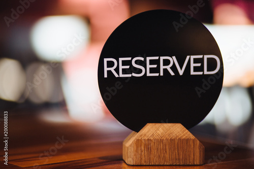 Close up of restaurant reserved table sign on table. Inscription denotes booked table in cafeteria. Don`t occupy this place! Table setting. Cafe desk for special occasion photo