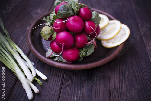 fresh radish onion and lemon on a clay plate on a wooden table, the concept of vegetarianism