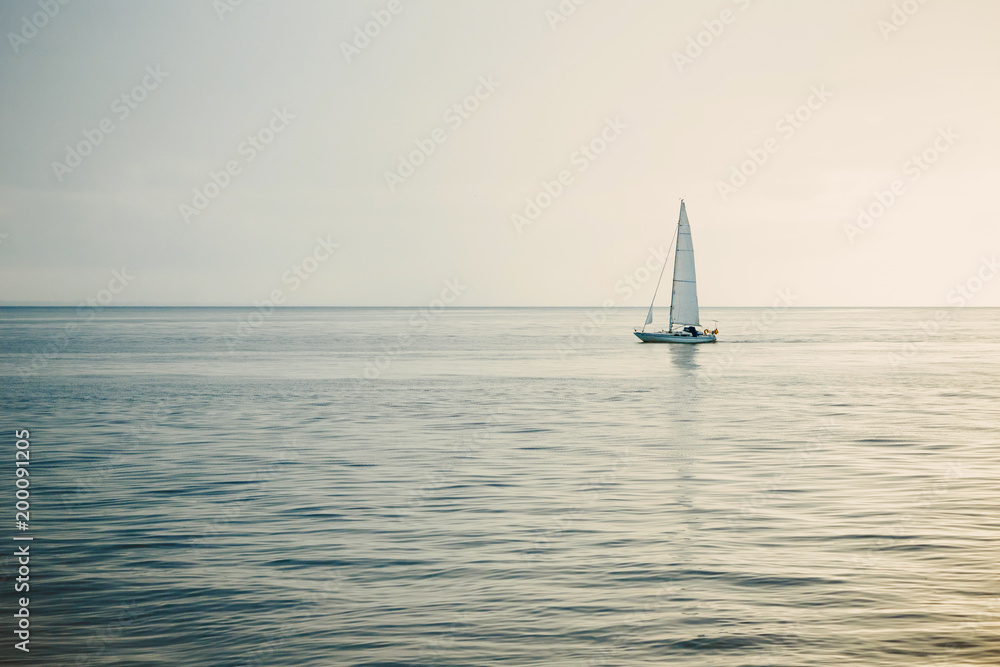 Sailing boat on open sea at sunset.