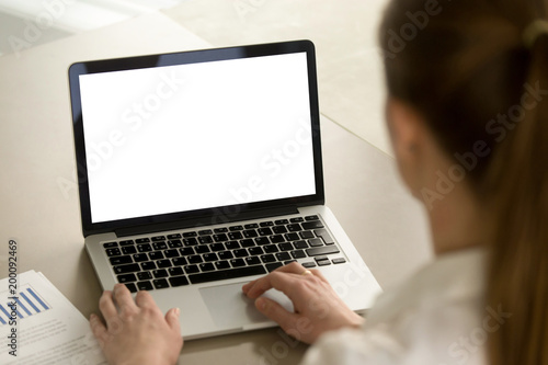 Businesswoman in office working on laptop with mockup blank screen. Empty copy space on monitor for business advertisement, corporate website, company financial report. Close up view, focus on screen.