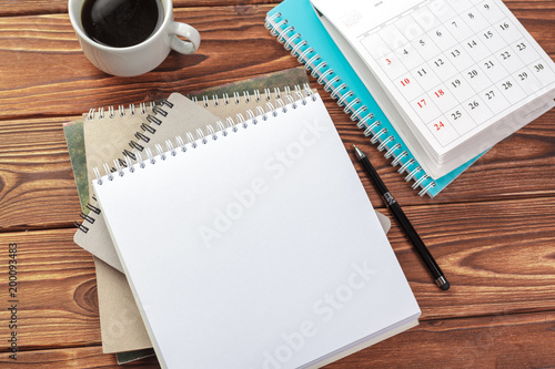 Office desk table top view. Notepad with blank pages on wooden table