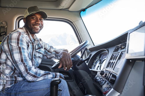 Black man truck driver in the cab of his commercial truck. photo