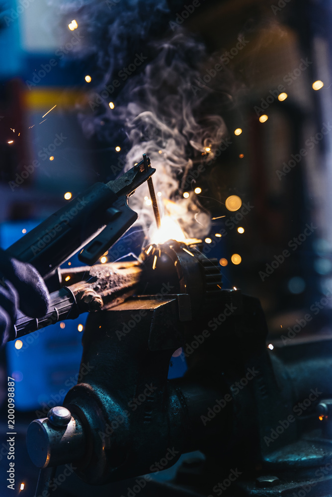 Mechanic man welding metal material in garage. Mechanic man welding metal material in garage.