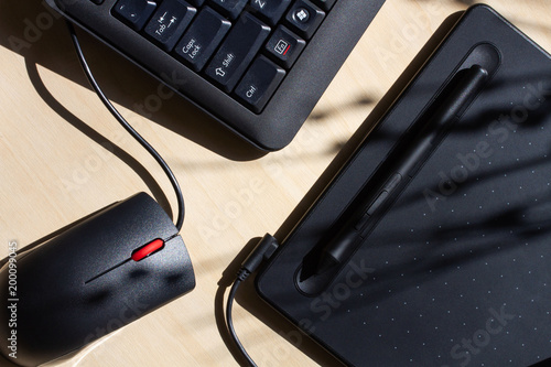 Office table with a graphic tablet, computer keyboard and mouse, black.