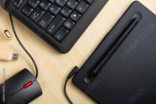 Office table with a graphic tablet, computer keyboard and mouse, black.