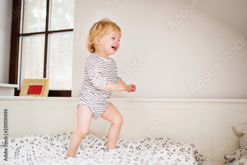 Cute toddler boy jumping on the bed.