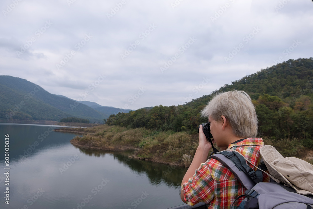 Young man trekker use digital camera take photo enjoy traveling with backpack, hiking concept, travel concept Young man trekker use digital camera take photo enjoy traveling with backpack, hiking concept, travel concept