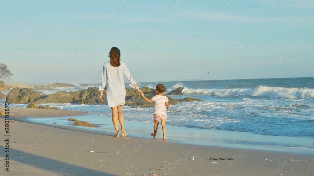 Mother with baby walking on sea coast with holding hands. Mother with baby walking on sea coast with holding hands.
