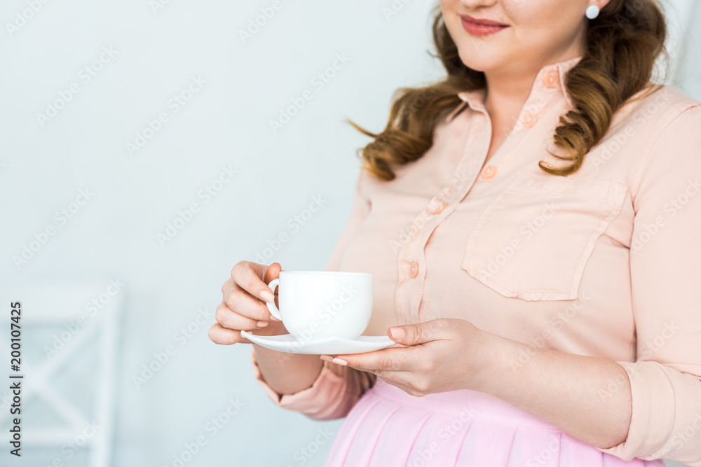 cropped image of woman holding cup of coffee at kitchen cropped image of woman holding cup of coffee at kitchen