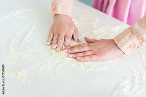 cropped image of woman spreading flour on kitchen counter