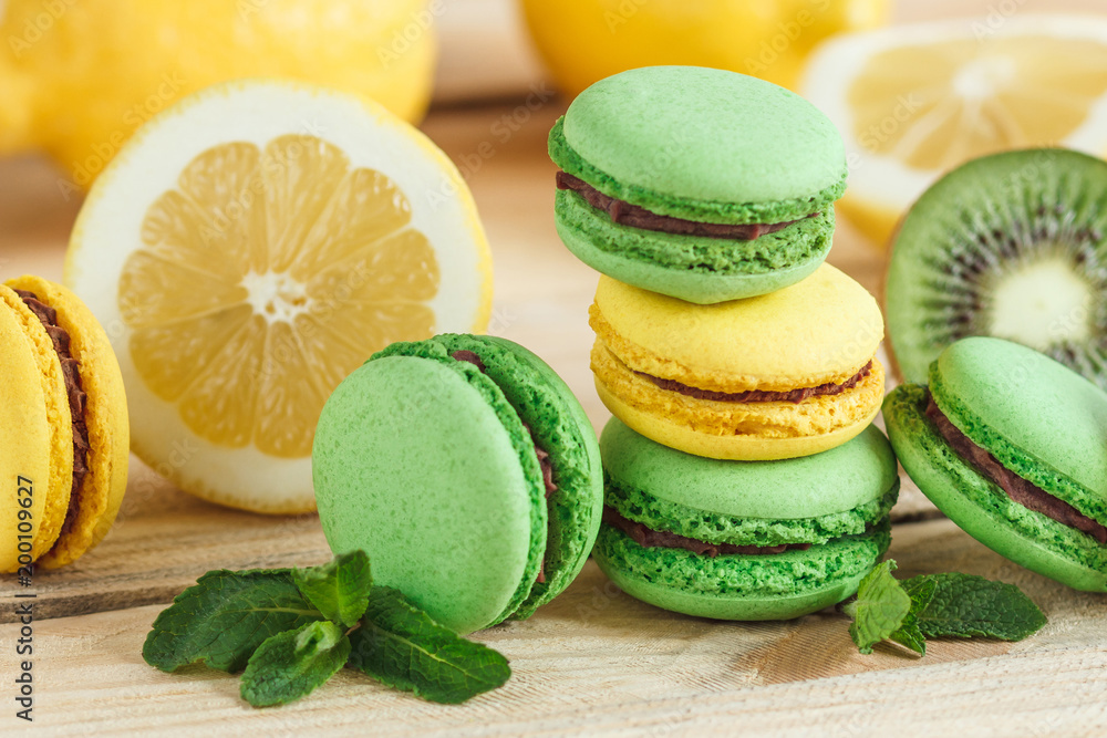 Green and yellow french macarons with kiwi, lemon and mint decorations Green and yellow french macarons with kiwi, lemon and mint decorations