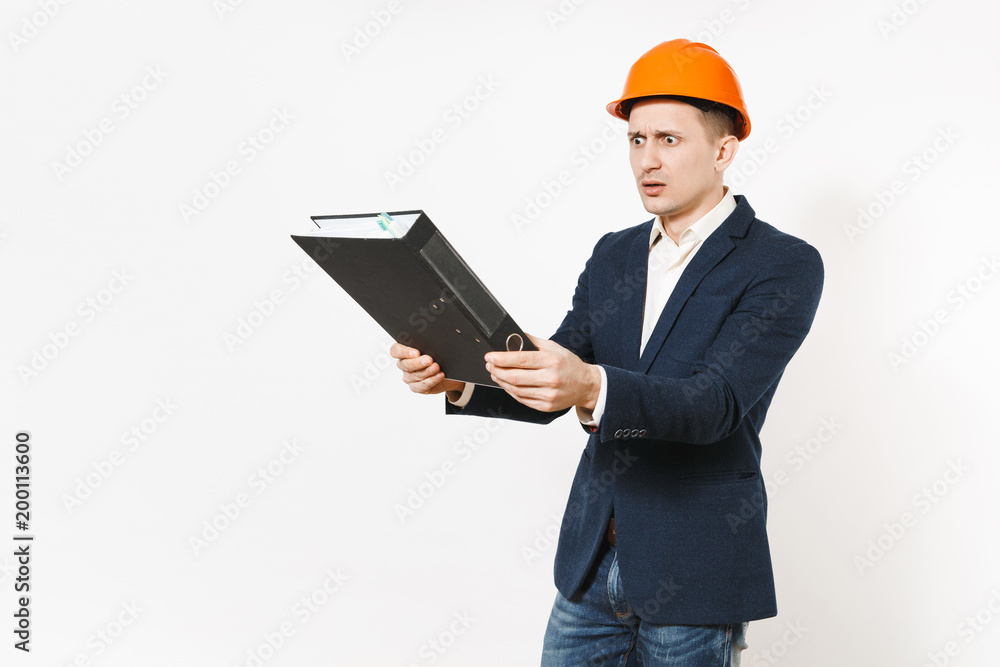 Irritated dissatisfied businessman in dark suit, protective construction helmet holding black folder for papers document isolated on white background. Male worker for advertisement. Business concept. Irritated dissatisfied businessman in dark suit, protective construction helmet holding black folder for papers document isolated on white background. Male worker for advertisement. Business concept.