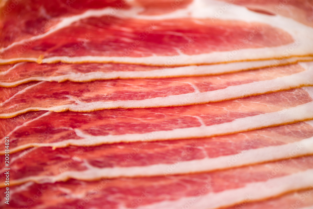 Sliced italian prosciutto background. Top view, copy space. Prosciutto texture close up. Sliced italian prosciutto background. Top view, copy space. Prosciutto texture close up.