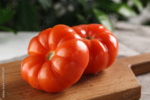 two fresh red tomatoes on cutting board