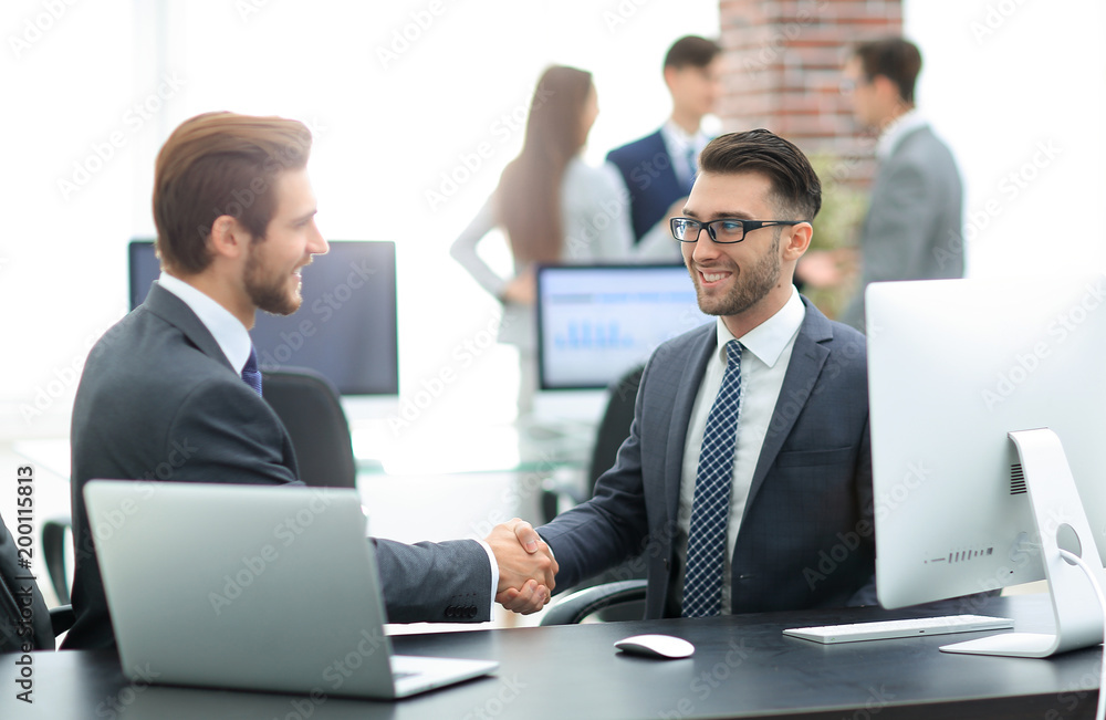 Successful managers shaking hands after closing deal in office Successful managers shaking hands after closing deal in office