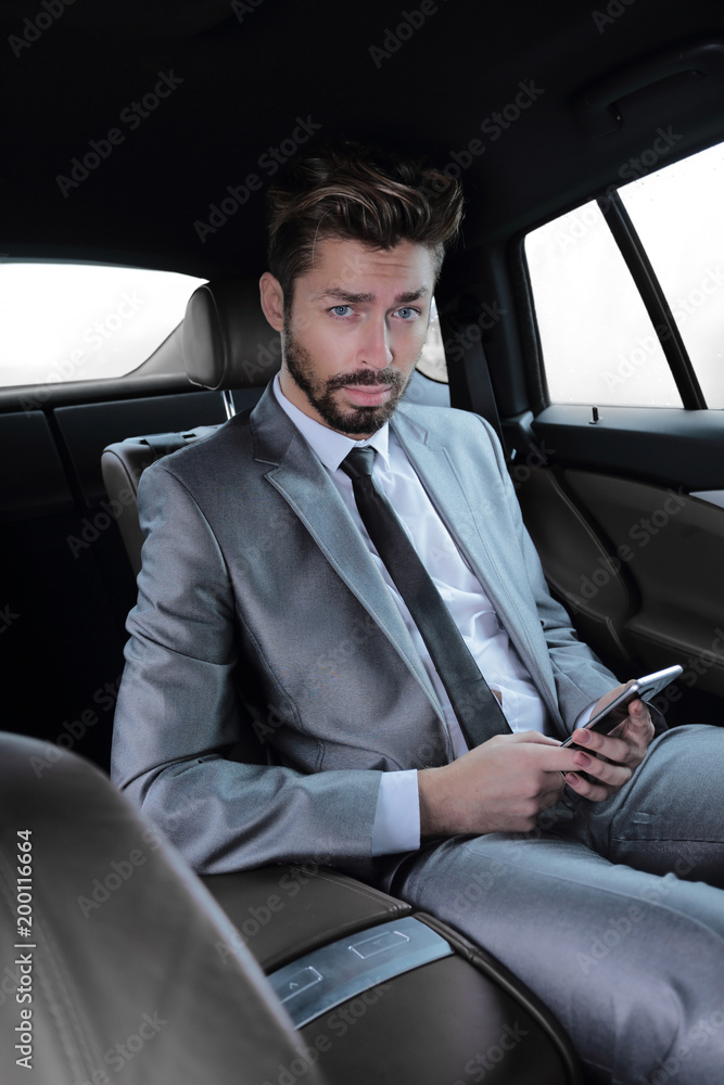 man in suit sitting in car and reading messages on smartphone man in suit sitting in car and reading messages on smartphone