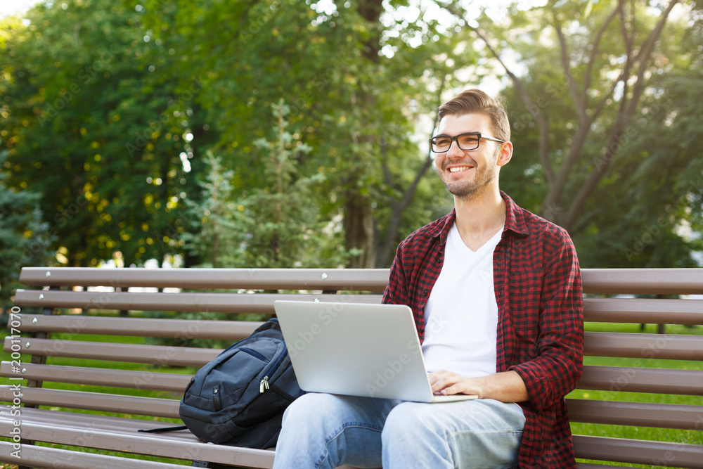 Happy young man with laptop outdoors