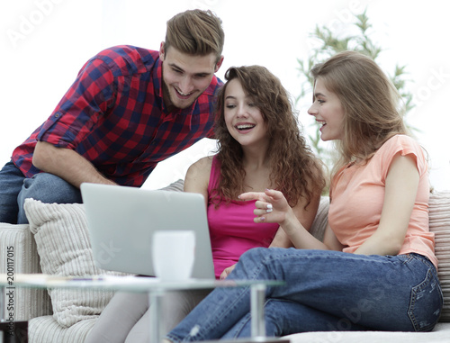 group of students looking at a laptop screen,sitting on the couch