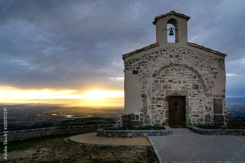 French landscape. Panoramic view over the Rhone valley to the Vercors and the Alps in the background at sunrise and small chapel in the foreground. French landscape. Panoramic view over the Rhone valley to the Vercors and the Alps in the background at sunrise and small chapel in the foreground.