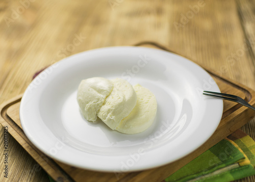 Mozzarella on a plate on a wooden background.