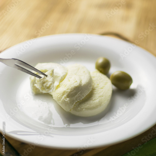 Cheese mozzarella and olives on a plate on a wooden background.