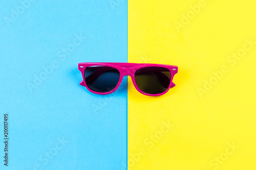 Red sunglasses on bright blue and yellow background.