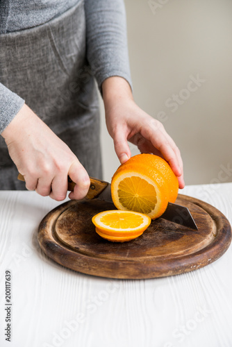 Woman cuts orange on board close