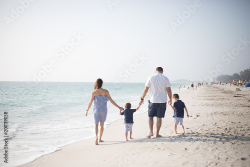 Family with Young Boys Holding Hands and Walking Down the Coastline at the Beach