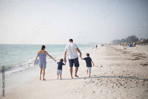 Family with Young Boys Holding Hands and Walking Down the Coastline at the Beach