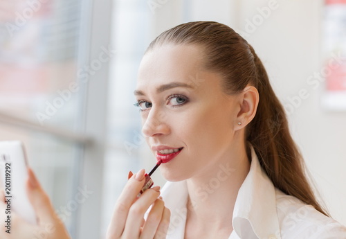 Face woman, paints lips lipstick