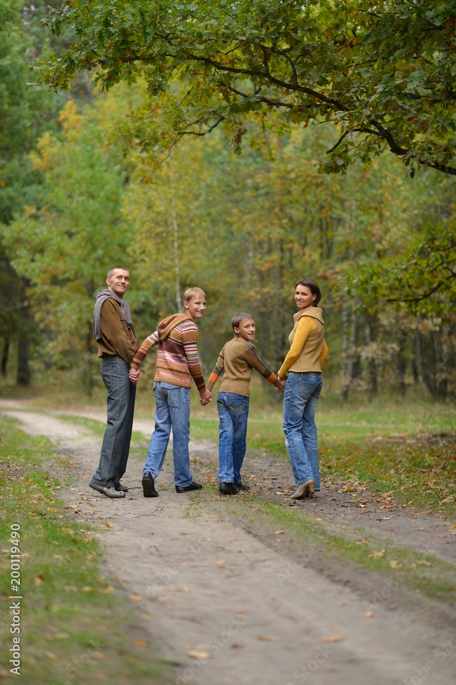Family in autumn forest looking back