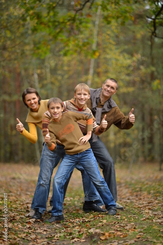 Family in autumn forest with thumbs up