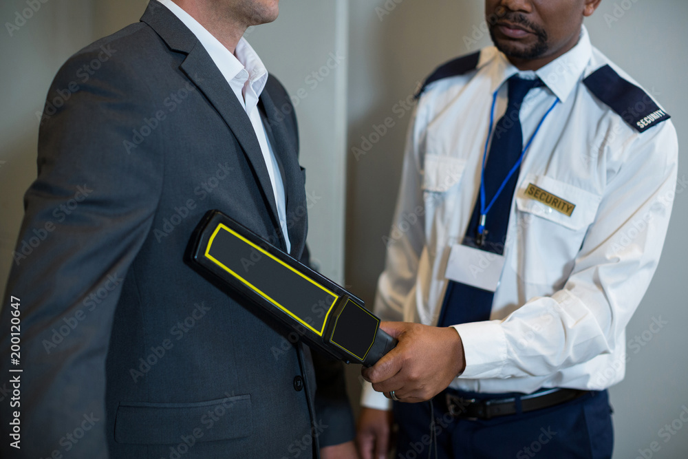 Airport security officer using a hand held metal detector to check a