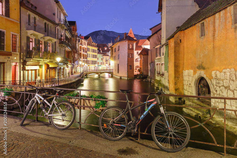 Fototapeta premium The Palais de l'Isle, bridge with bikes and Thiou river during morning blue hour in old city of Annecy, Venice of the Alps, France